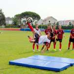 Otto ragazzi svolgono l'allenamento per migliorare il calcio in acrobazia (rovesciata) durante il campo estivo di calcio dell'AC Milan