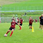 Um técnico da equipe técnica do Sporteventi orienta cinco jovens do AC Milan Academy Camp no tiro à distância