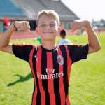 Bambino dell'AC Milan Camp mostra i muscoli per far capire quanto è forte a giocare a calcio