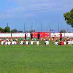 Giovani calciatori dell'AC Milan Junior Camp nel cerchio di metà campo mentre ricevono le istruzioni dallo staff tecnico di Sporteventi