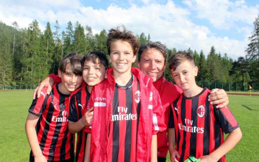 O ex-jogador de futebol Stefano Eranio abraça quatro crianças que ele treina durante a escola de futebol de verão do AC Milan