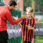 Un allenatore dello staff dell'AC Milan Junior Camp si complimenta con il giovane calciatore