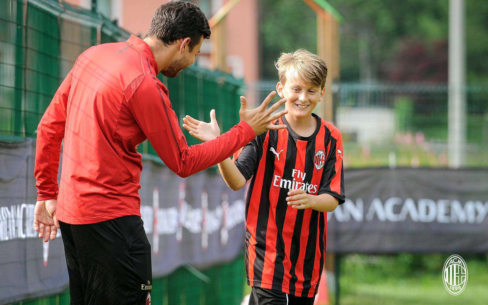 Un allenatore dello staff dell'AC Milan Junior Camp si complimenta con il giovane calciatore