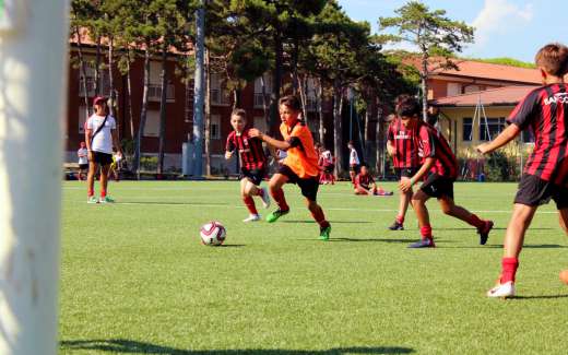 Cinco crianças engajadas em futebol durante o treinamento no AC Milan Academy Camp