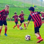 Cinque bambini con la maglia dell'AC Milan impegnati in un'azione durante gli allenamenti al campo estivo di calcio