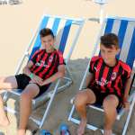 Dos muchachos de los campamentos de verano del AC Milan sentados en las sillas de playa en Lignano Sabbiadoro