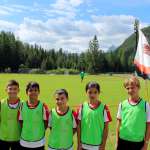 Sete crianças do AC Milan Academy Camp em frente ao campo de jogos de Cortina d'Ampezzo nas Dolomitas