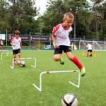 Bambini durante gli esercizi di salto ad ostacoli al Milan Junior Camp di Lignano Sabbiadoro