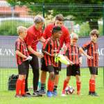Lorenzo Cresta e due tecnici dello staff di Sporteventi impartiscono le indacazioni a quattro bambini dell'AC Milan Junior Camp