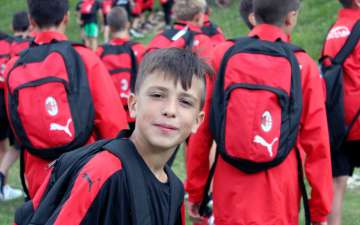 Ragazzo veste il kit sportivo Puma mentre si avvia agli allenamenti con altri ragazzi dell'AC Milan Camp