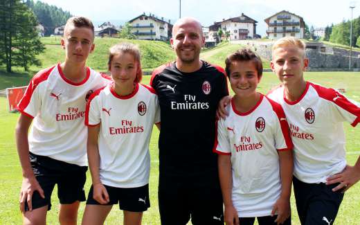 A member of the Sporteventi staff with three boys and a girl during the day at the AC Milan Academy Camp